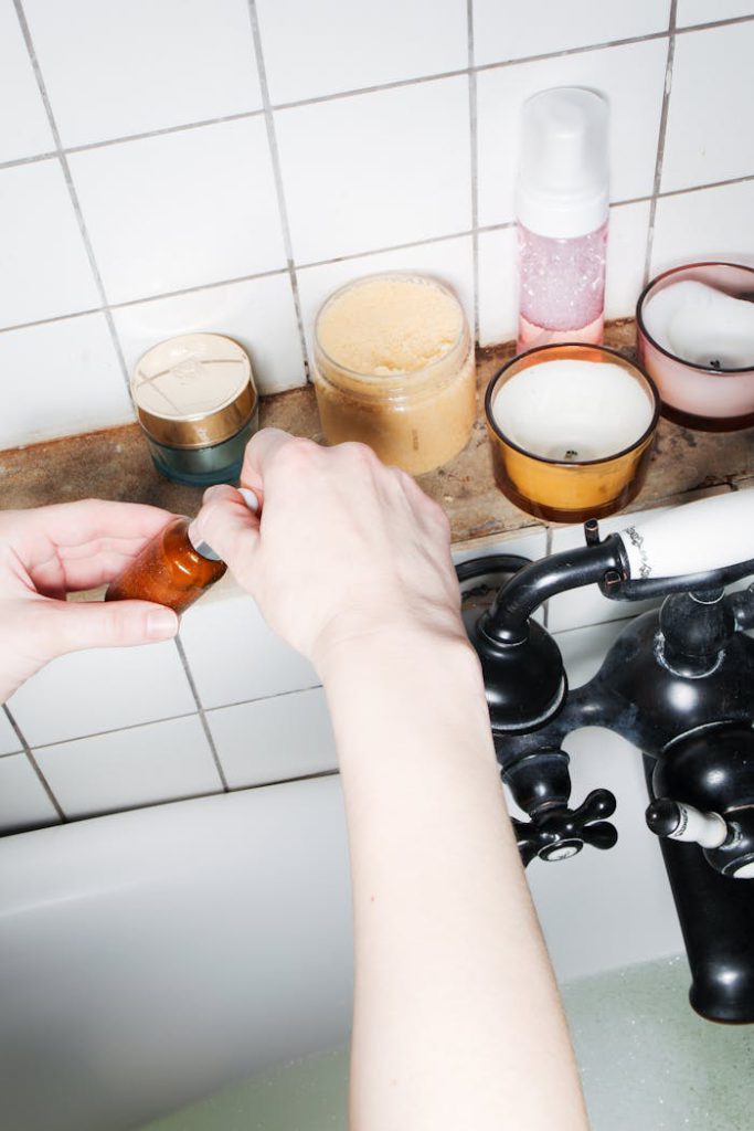 pexels-photo-5849416 Hands adjusting vintage tap with bath essentials on white tiles.