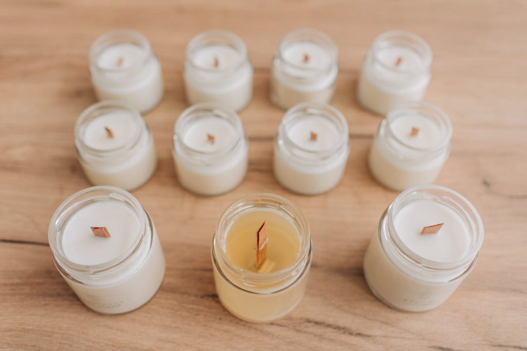 Top-down view of minimalistic white and yellow jar candles on wooden surface.