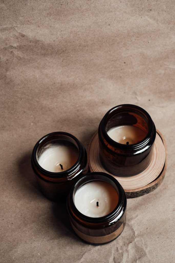 Three scented candles in amber glass jars arranged on a wooden slice, creating a cozy atmosphere.