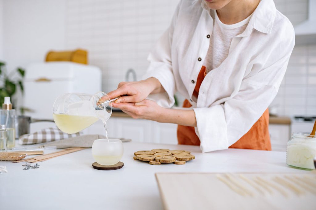 pexels-photo-7234549 A craftswoman pouring wax into a candle mold in a cozy kitchen. Perfect for DIY and crafting themes.