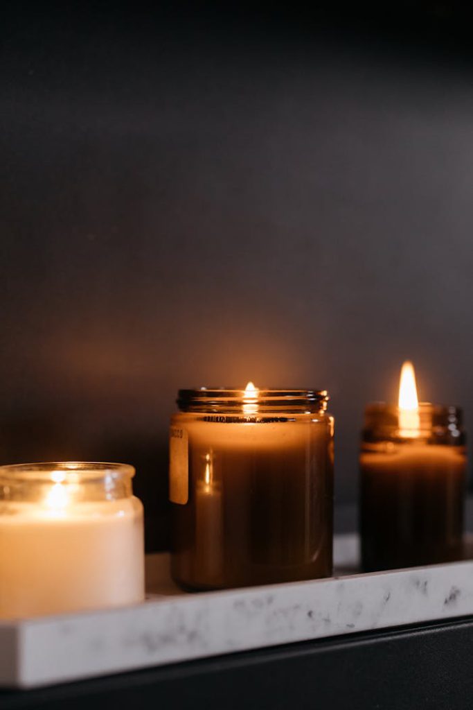 A soothing display of burning candles in glass jars on a marble surface.